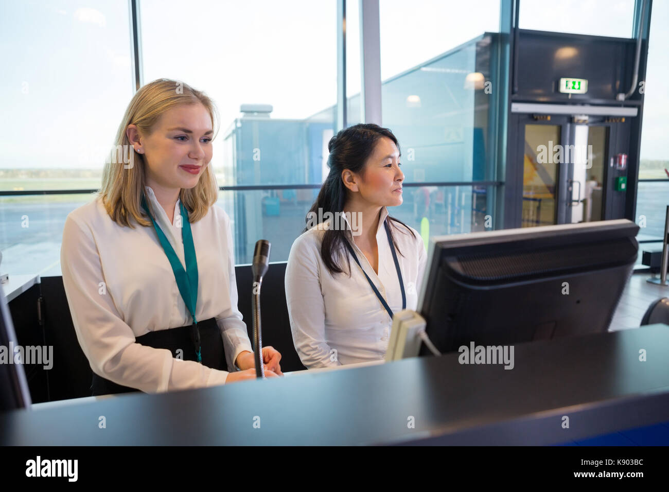 Gli addetti della reception seduta a help desk in aeroporto Foto Stock