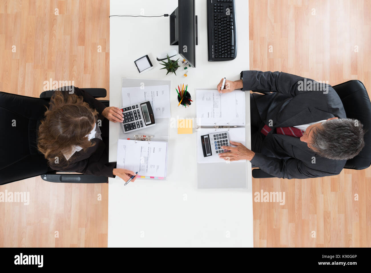 Angolo di alta vista di due imprenditori il calcolo di fatture in ufficio Foto Stock