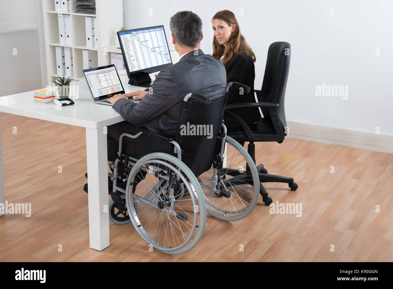 Coppia disabilitato imprenditore e imprenditrice lavorando insieme sul computer in ufficio Foto Stock
