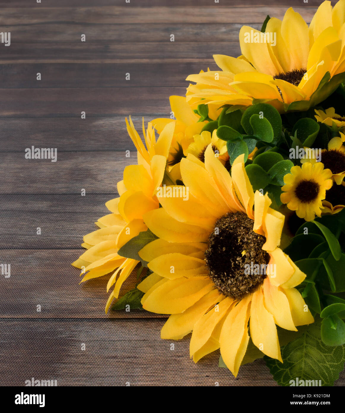 Primo piano di un mazzo di fiori di girasole in legno marrone scuro dello sfondo con un sacco di spazio copia. Foto Stock