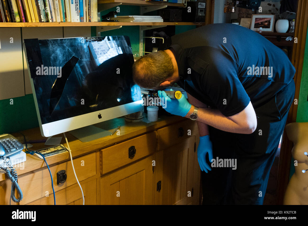 Una scena di polizia di criminalità officer (soco) in una casa a lavorare la verifica di un danneggiato imac 27' computer per le impronte digitali da sinistra di ladri, Regno Unito Foto Stock Una scena di polizia di criminalità officer (soco) in una casa a lavorare la verifica di un danneggiato imac 27' computer per le impronte digitali da sinistra di ladri, Regno Unito Foto Stock