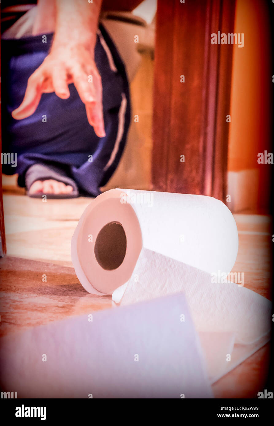 Uomo seduto in bagno provato a prendere il rotolo di carta igienica, immagine concettuale Foto Stock