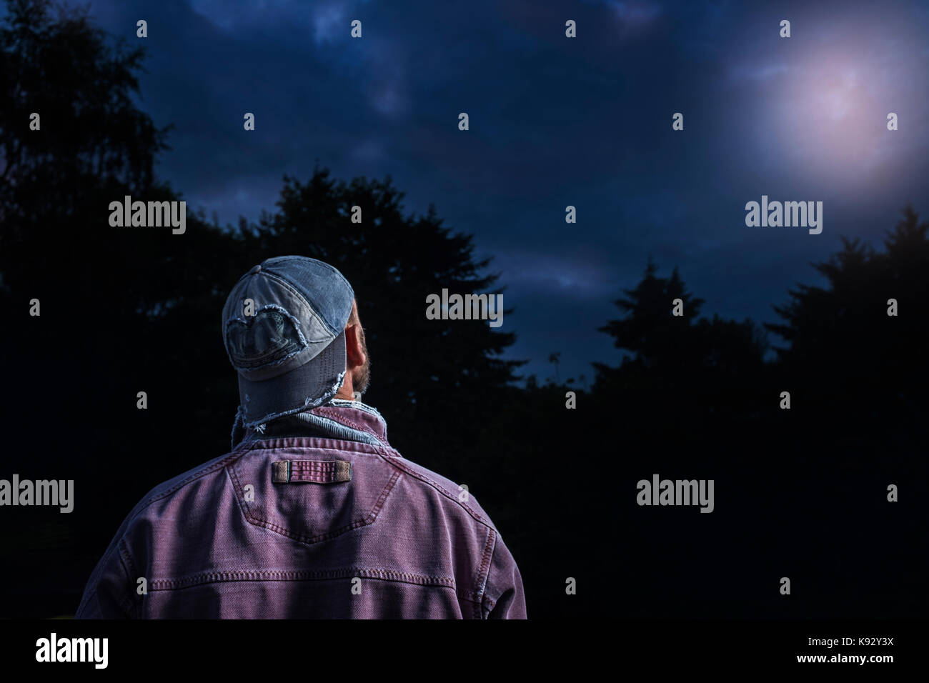 Un uomo che guarda verso un bagliore nel cielo notturno. Foto Stock