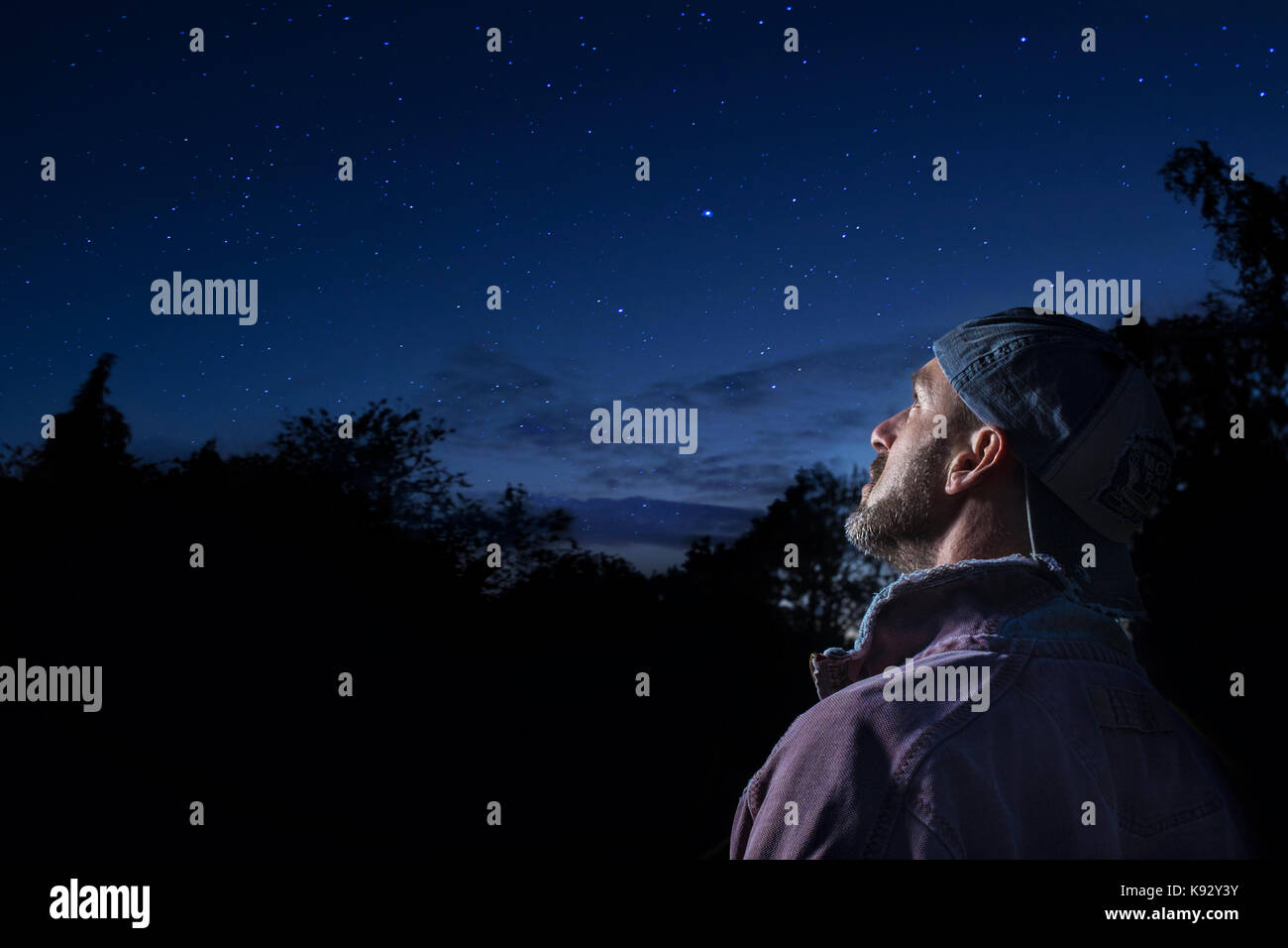 Un uomo che guarda verso le stelle nel cielo notturno. Foto Stock