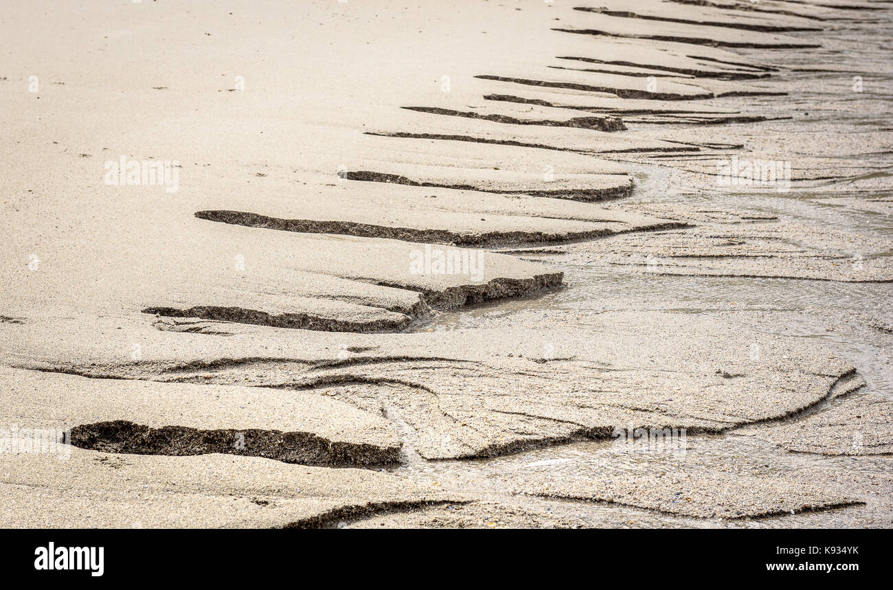 Afflusso di acqua dolce nell oceano su spiaggia sabbiosa. i flussi di acqua causato dalla bassa marea provoca erosione della sabbia e canale di specifiche strutture simili. Foto Stock