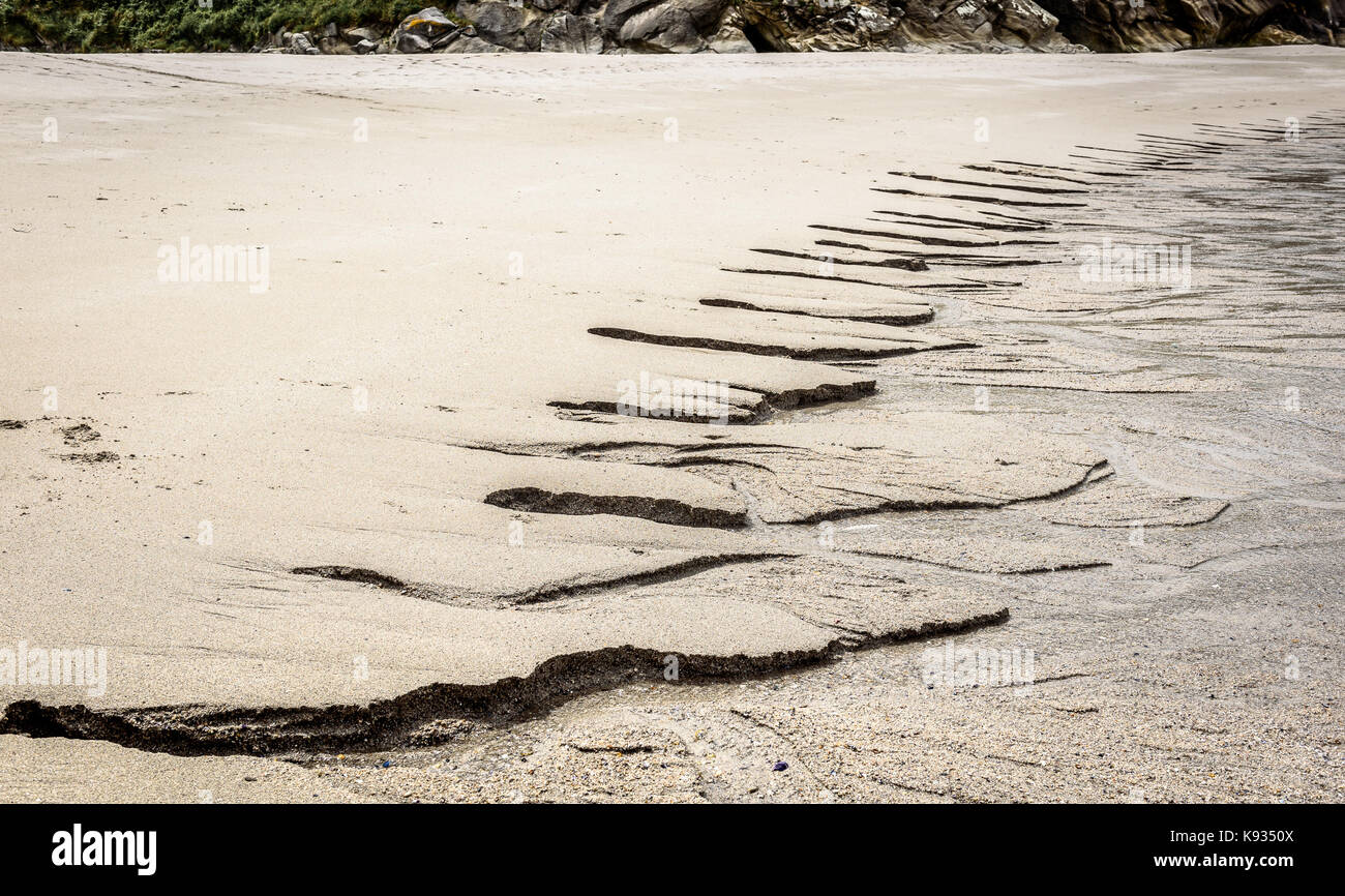 Afflusso di acqua dolce nell oceano su spiaggia sabbiosa. i flussi di acqua causato dalla bassa marea provoca erosione della sabbia e canale di specifiche strutture simili. Foto Stock