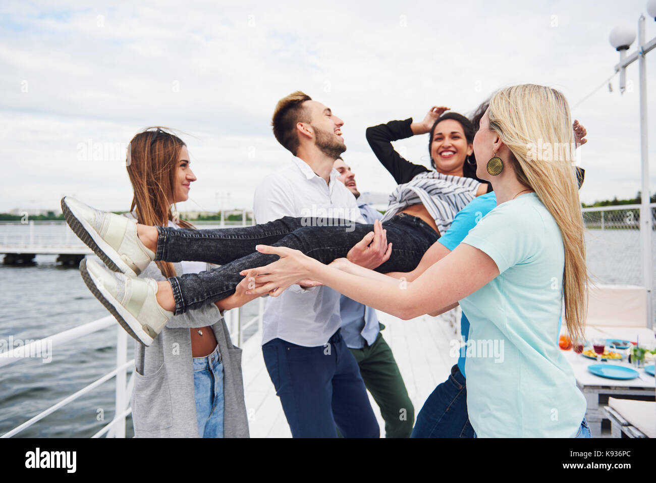 Gruppo di amici felici in spiaggia, uomo lanciare una donna felice. Foto Stock