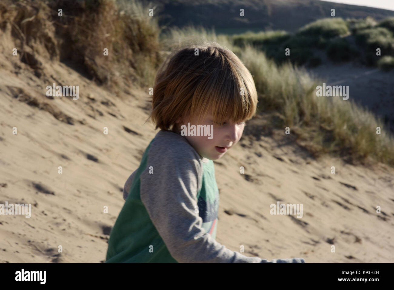 Un giovane ragazzo corre giù dune di sabbia sulla spiaggia. Foto Stock