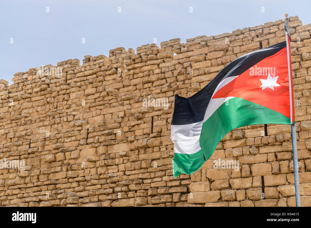 Giordano battenti bandiera al di fuori del muro di pietra di kerak castello, un castello crociato di al-karak. Foto Stock