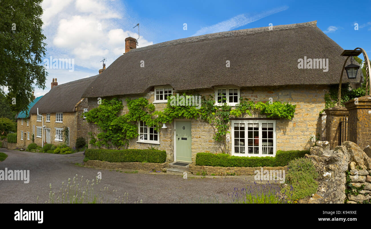 Cottage con il tetto di paglia in inglese il Cotswolds. Foto Stock