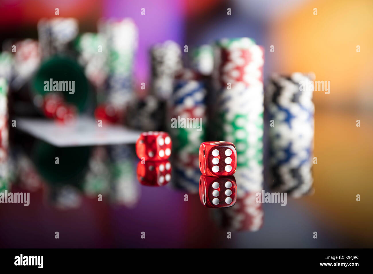 Casino tema. Alto contrasto immagine del casino roulette, poker, gioco di dadi, Poker chips su un tavolo da gioco, tutti su colorato sfondo bokeh di fondo. Foto Stock