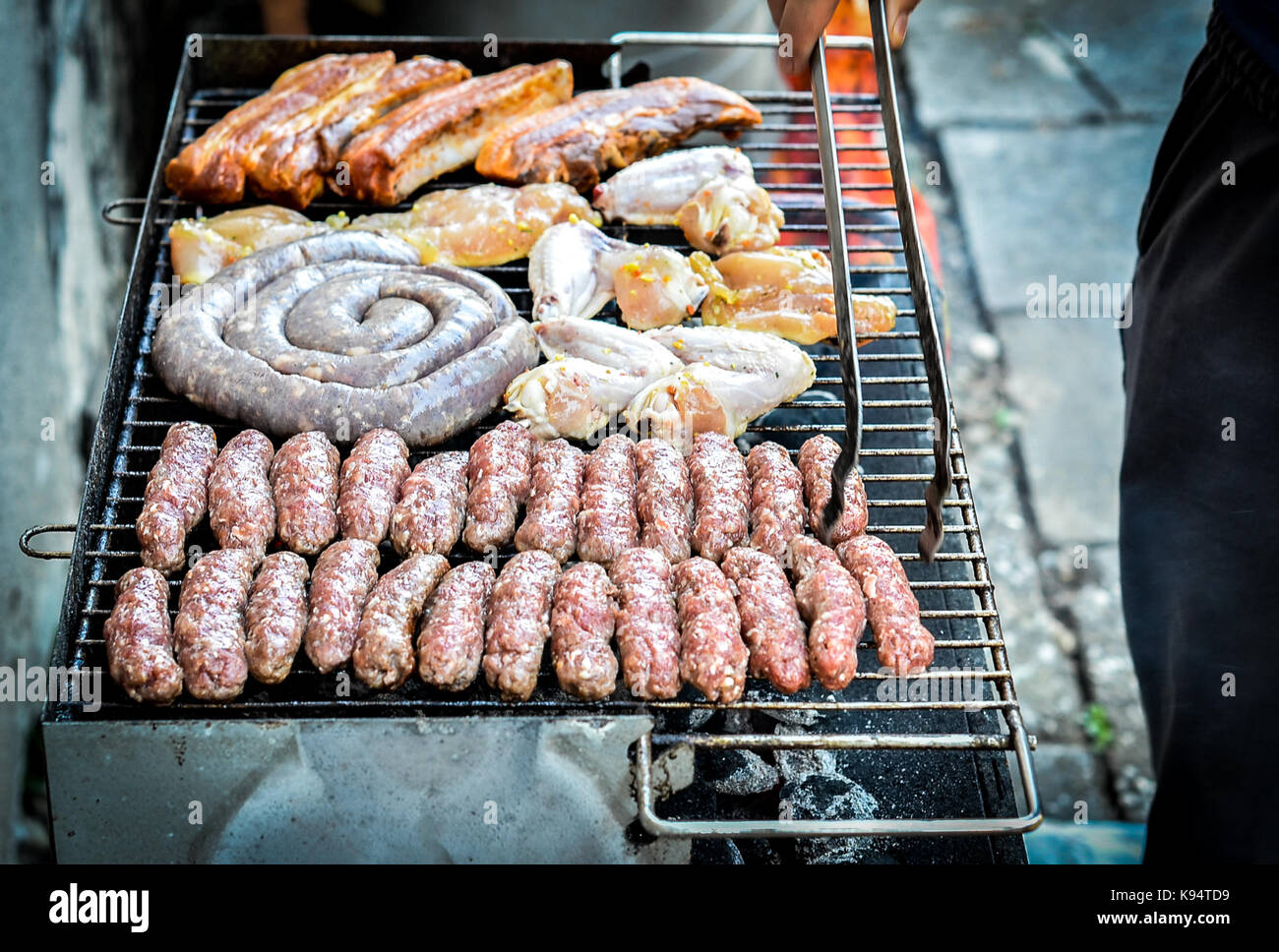 Misto di diverse varietà di carne sul grill barbecue a carbone. cevapcici, salsicce, ali di pollo e hot dogs sul barbecue a carbone per barbecue. Foto Stock