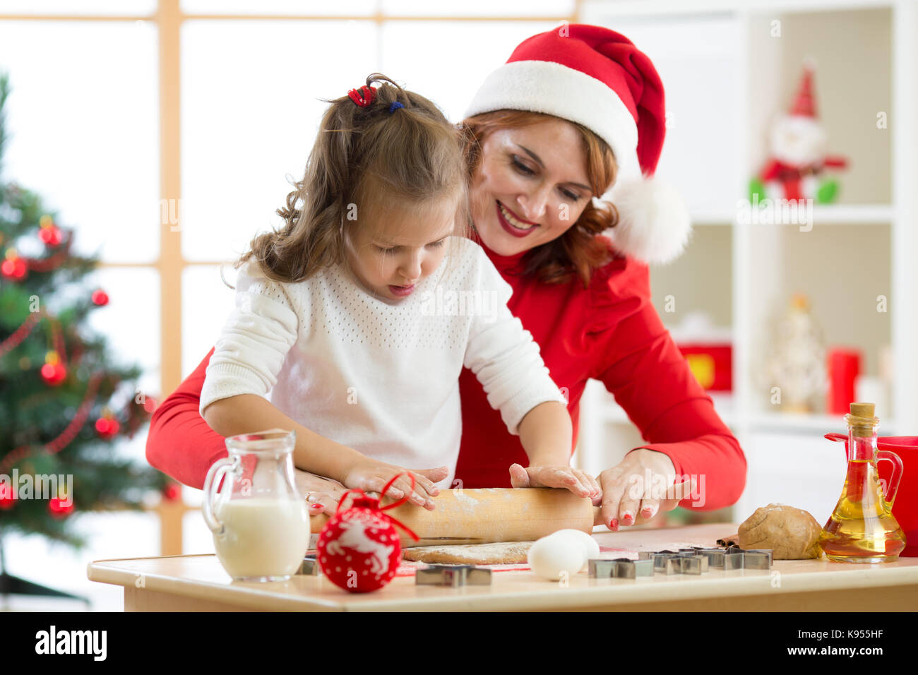 La famiglia la madre e il bambino rotolare la pasta, cuocere biscotti di Natale in festival sala decorata Foto Stock
