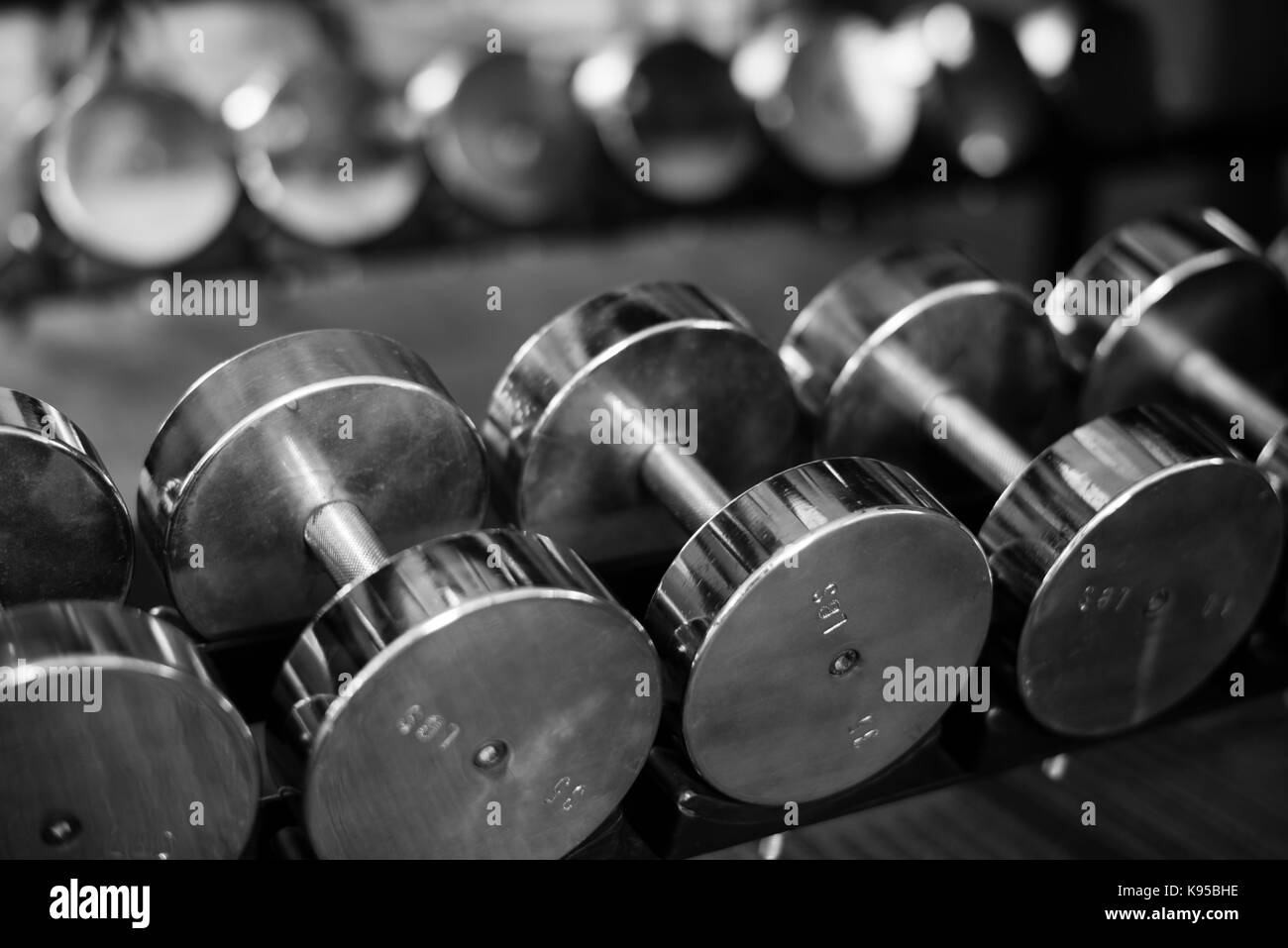 Righe di pesi su un rack in una palestra Foto Stock