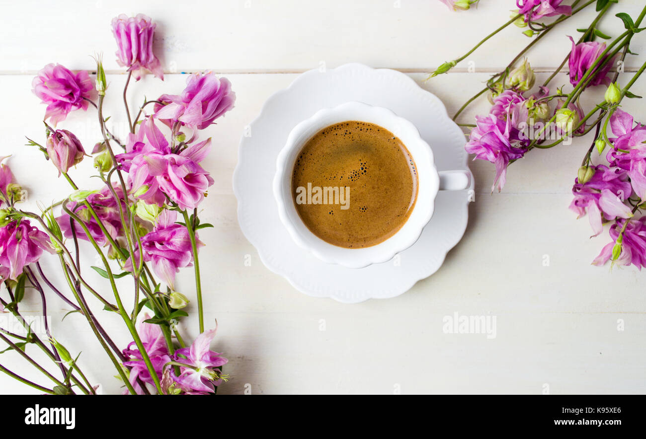 Tazza di caffè su una tavola decorata con fiori viola Foto Stock