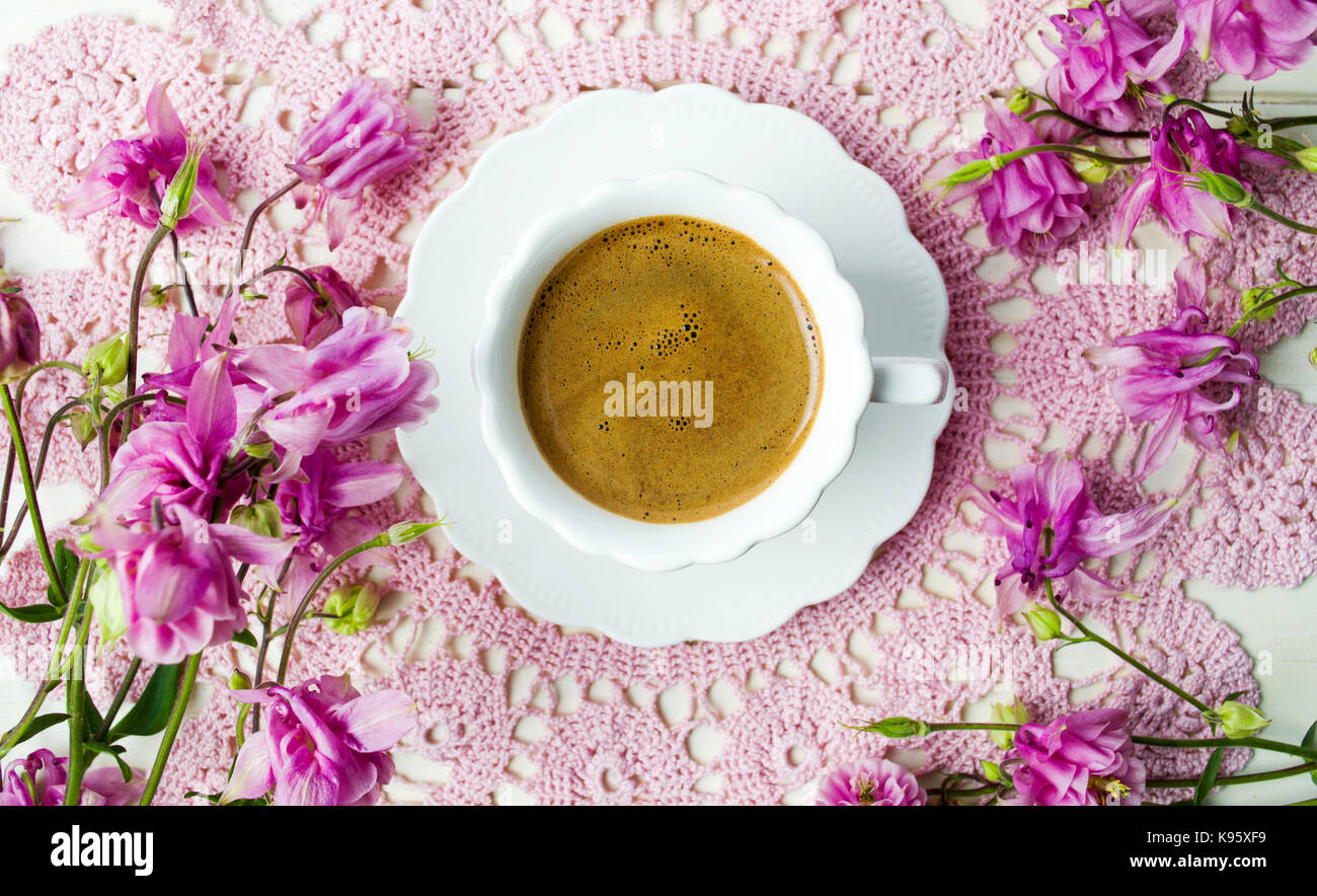 Tazza di caffè su una tavola decorata con fiori viola Foto Stock