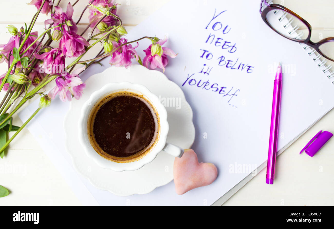 Tazza di caffè e una motivazione messaggio con fiori viola Foto Stock