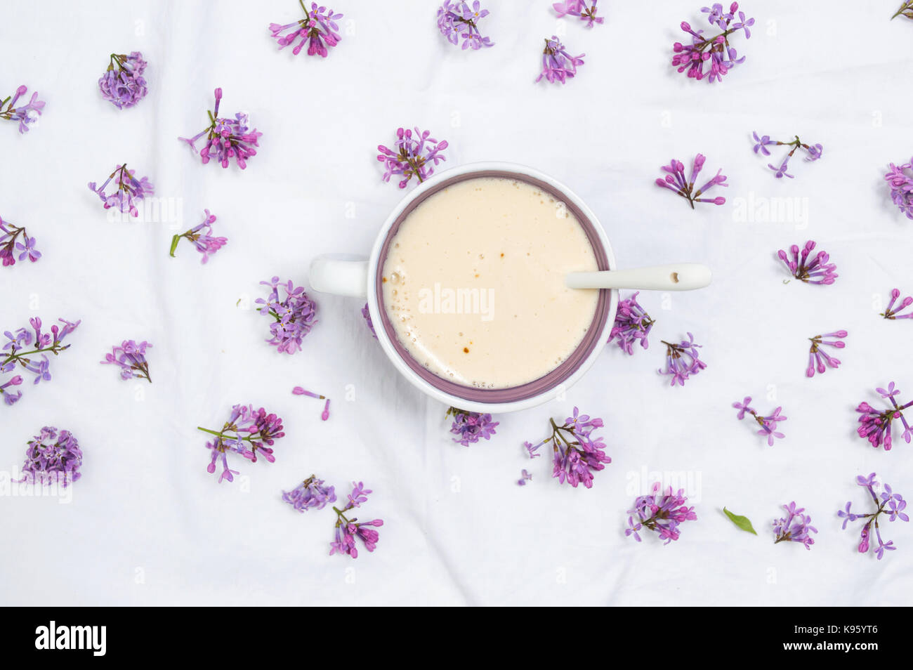 Caffè con latte e fiori viola sul tessuto bianco Foto Stock