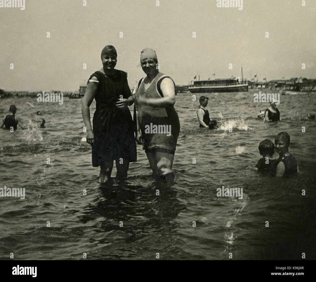 Antique c1920 fotografia, due donne nel periodo in costume da bagno in un famoso lago balneabile, con barche in background. Posizione sconosciuta, probabilmente la Nuova Inghilterra. Fonte: fotografia originale. Foto Stock