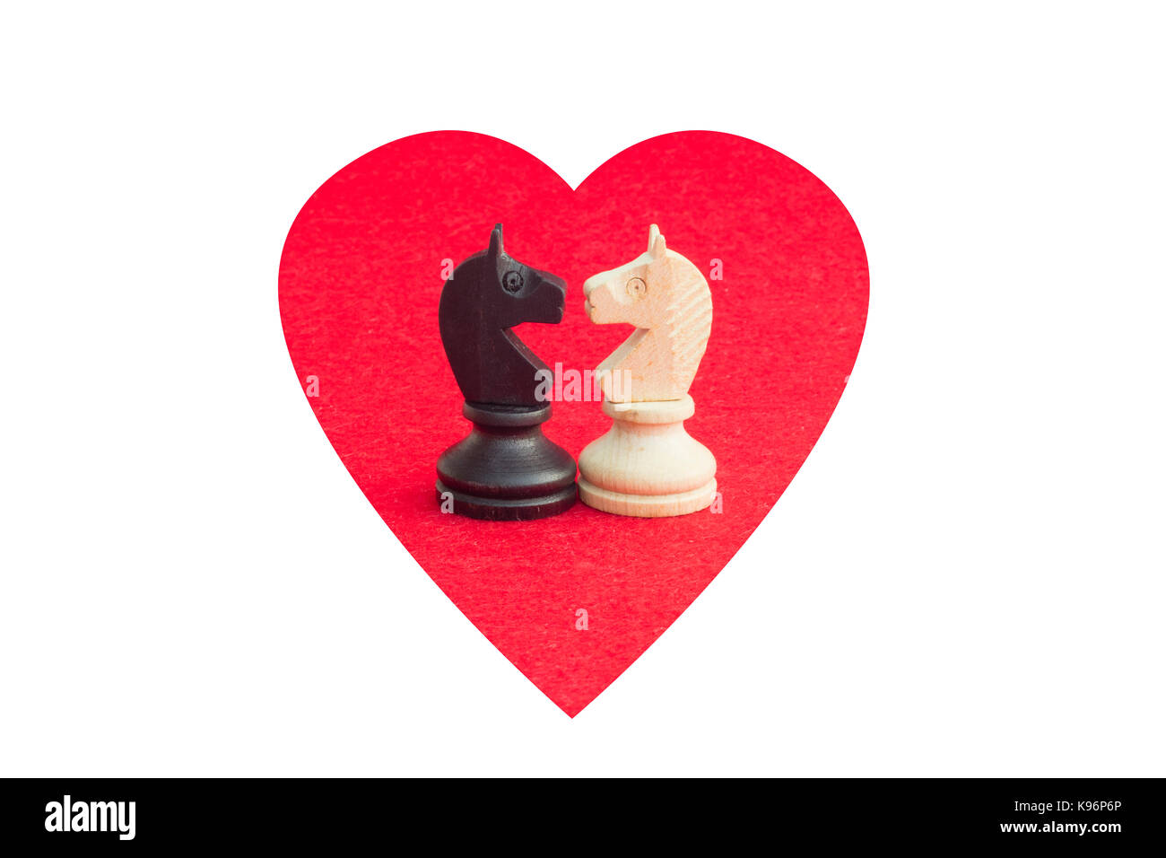 Cavallo bianco e cavallo nero, tradizionalmente affrontato nel gioco degli scacchi, sono riconciliati. Immagine in background isolato con forma di cuore. Foto Stock