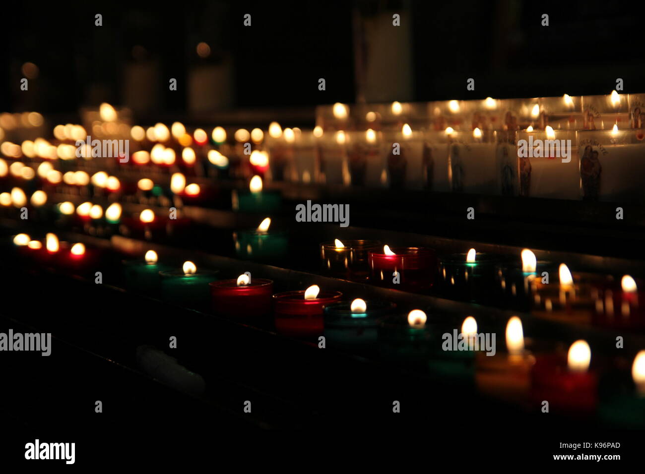 Messa a fuoco poco profonda shot di righe di candele votive in una chiesa cattolica Foto Stock