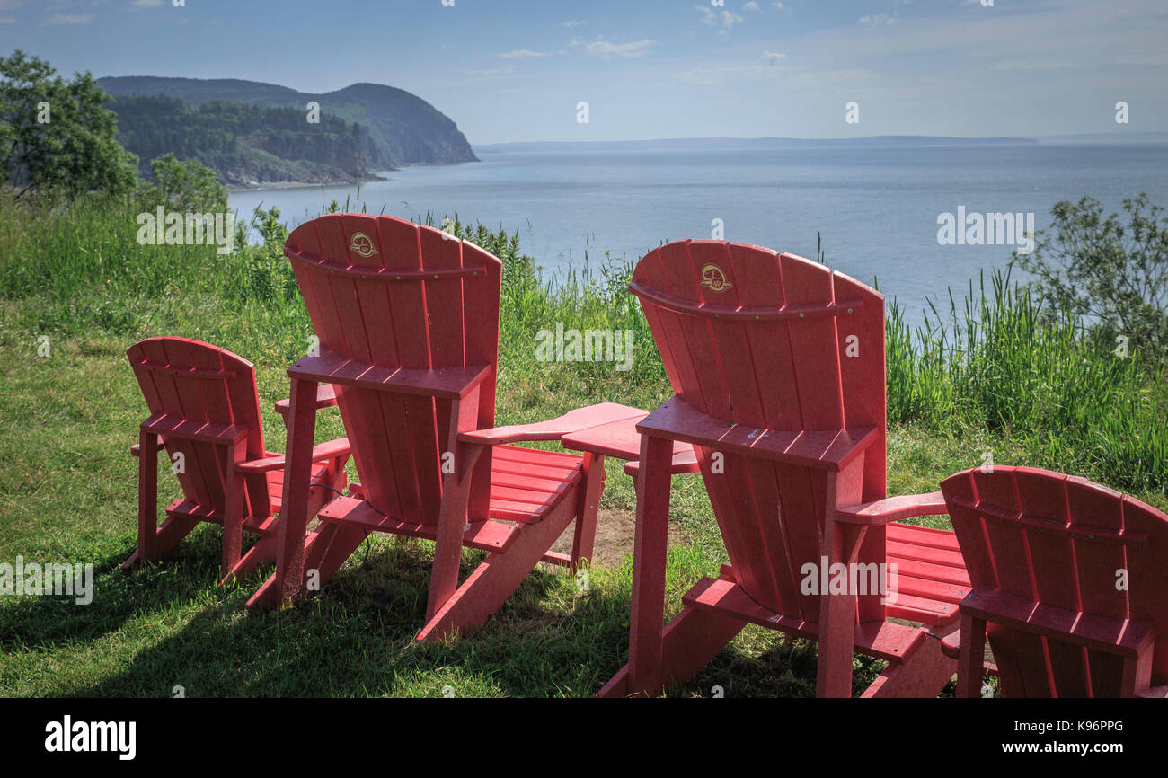 I colori vivaci dei outdoor sedie a sdraio rivolta verso le acque calme della baia di Fundy, New Brunswick, Canada Foto Stock
