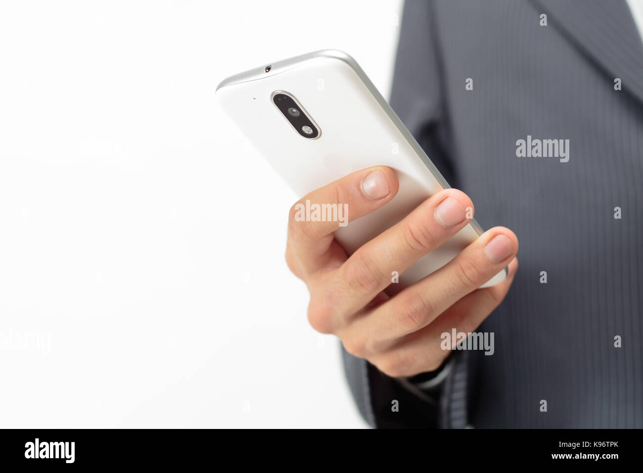 Uomo d'affari con un cellulare bianco in mano. Abito a righe bianco e grigio sullo sfondo. Foto Stock