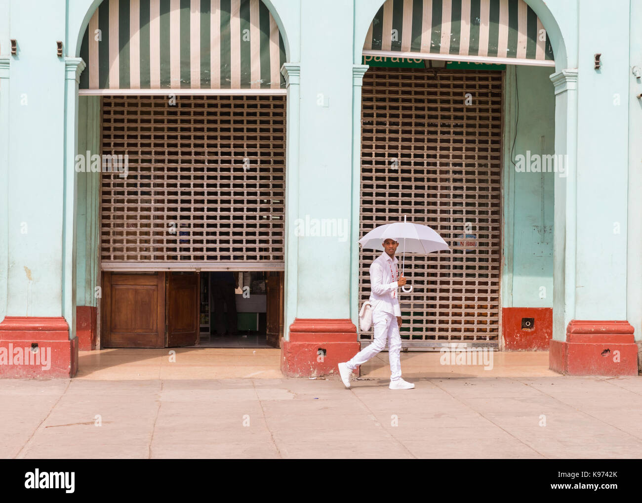 Giovane uomo cubano, Santeria religione avviare e credente indossando tutti i vestiti di bianco a piedi in strada, Havana, Cuba Foto Stock
