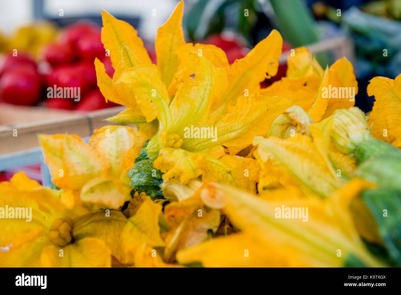 Aprire giallo fiore di zucchine mazzetto fuoco selettivo dettaglio stallo del mercato in background Foto Stock