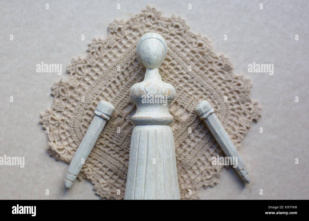 Un vecchio legno bambola femmina con bracci staccato, contro un vecchio centrino. Foto Stock
