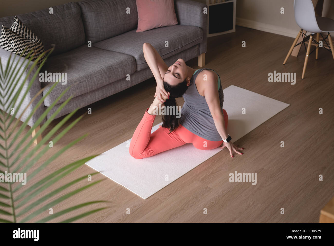 Angolo di Alta Vista della giovane donna facendo uno zampe piccione re pongono mentre si esercita nel salotto di casa Foto Stock