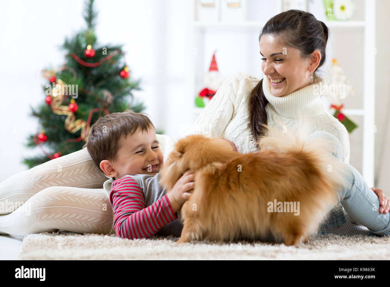 La donna e suo figlio e cane godendo di coccole in tempo di Natale Foto Stock