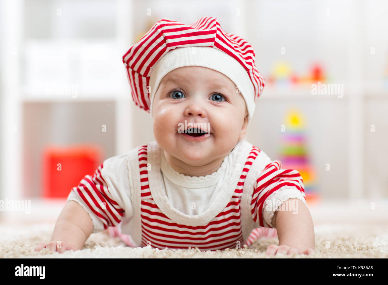 Bambino di sei mesi ragazza distesa su un tappeto sul pavimento in vivaio Foto Stock