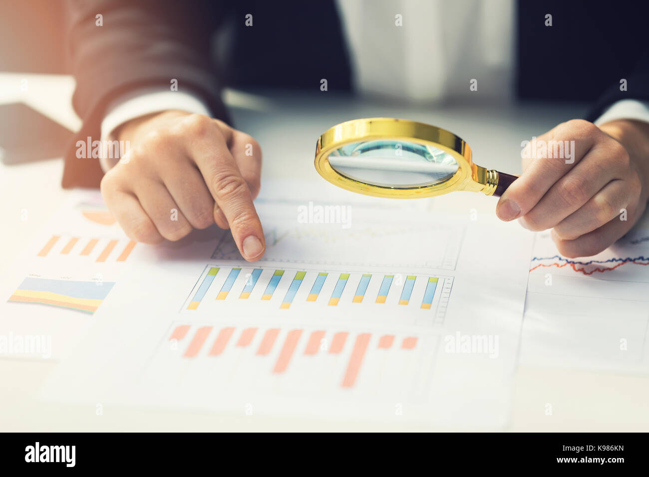 Le donne di business utilizzando la lente di ingrandimento per esaminare il riepilogo finanziario rapporto a grafico. concetto di auditing Foto Stock