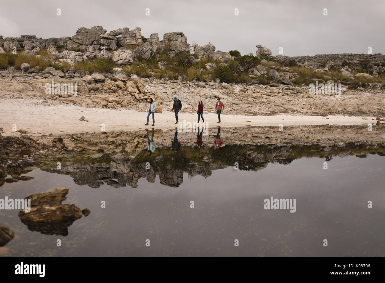 Gruppo di amici a piedi vicino al lago in una giornata di sole Foto Stock