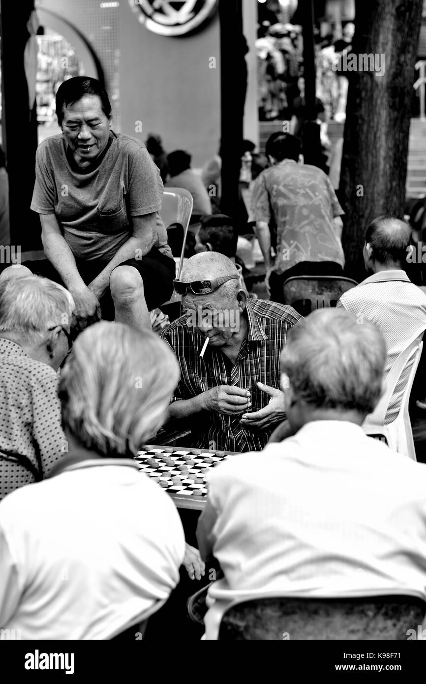 Un gruppo di anziani uomini cinesi la riproduzione di cinese tradizionale degli scacchi in Chinatown, Singapore Foto Stock