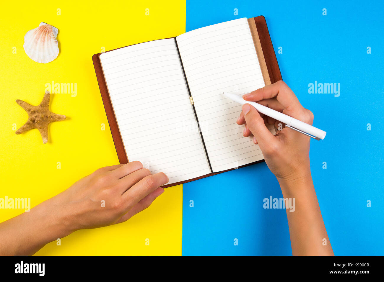 Viaggi, vacanze, estate concetto. donna la scrittura a mano in notebook su blu e sfondo giallo Foto Stock