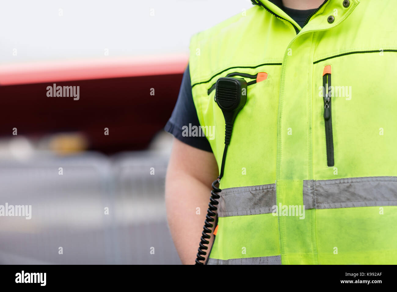 Lavoratore con microfono collegato sulla camicia riflettente all'aeroporto Foto Stock