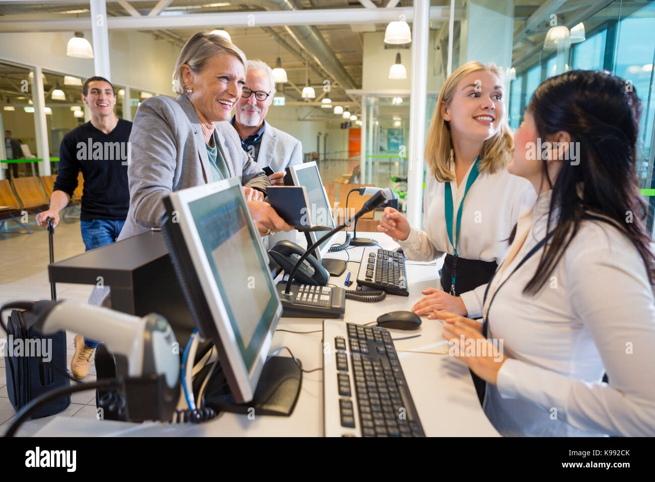 Imprenditrice guardando il personale femminile al check-in dell'aeroporto Foto Stock