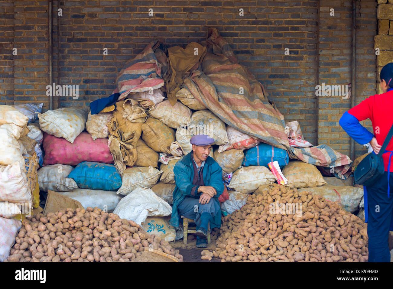 Lijiang, Cina - 30 Settembre 2007: patata cinese venditore la vendita di pile e sacchi di patate ad un mercato locale in Lijiang, Yunnan, Cina Foto Stock