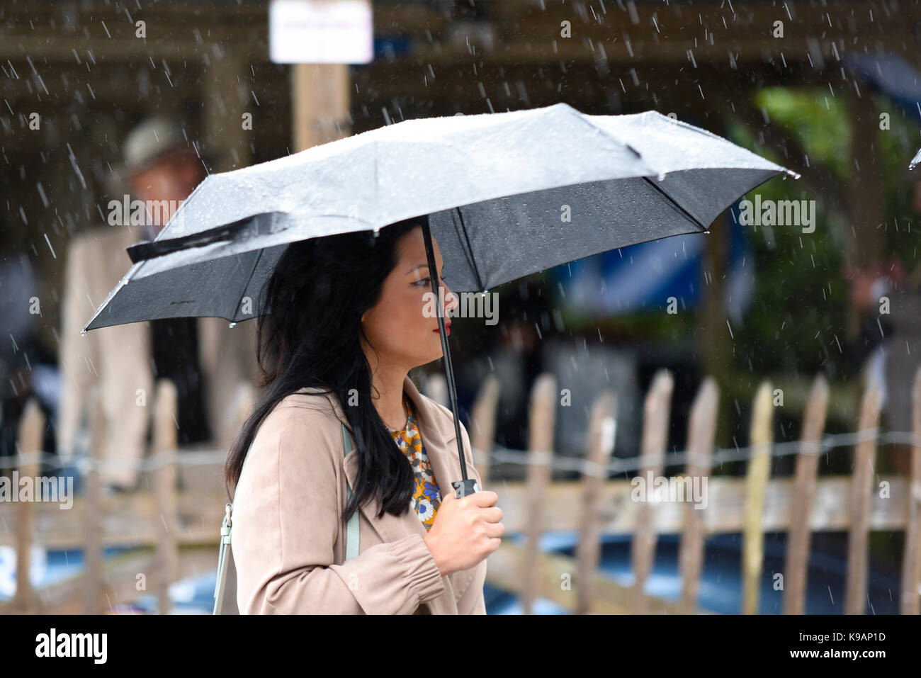 Una ragazza con ombrello sotto la pioggia al Goodwood Revival 2017 Foto Stock