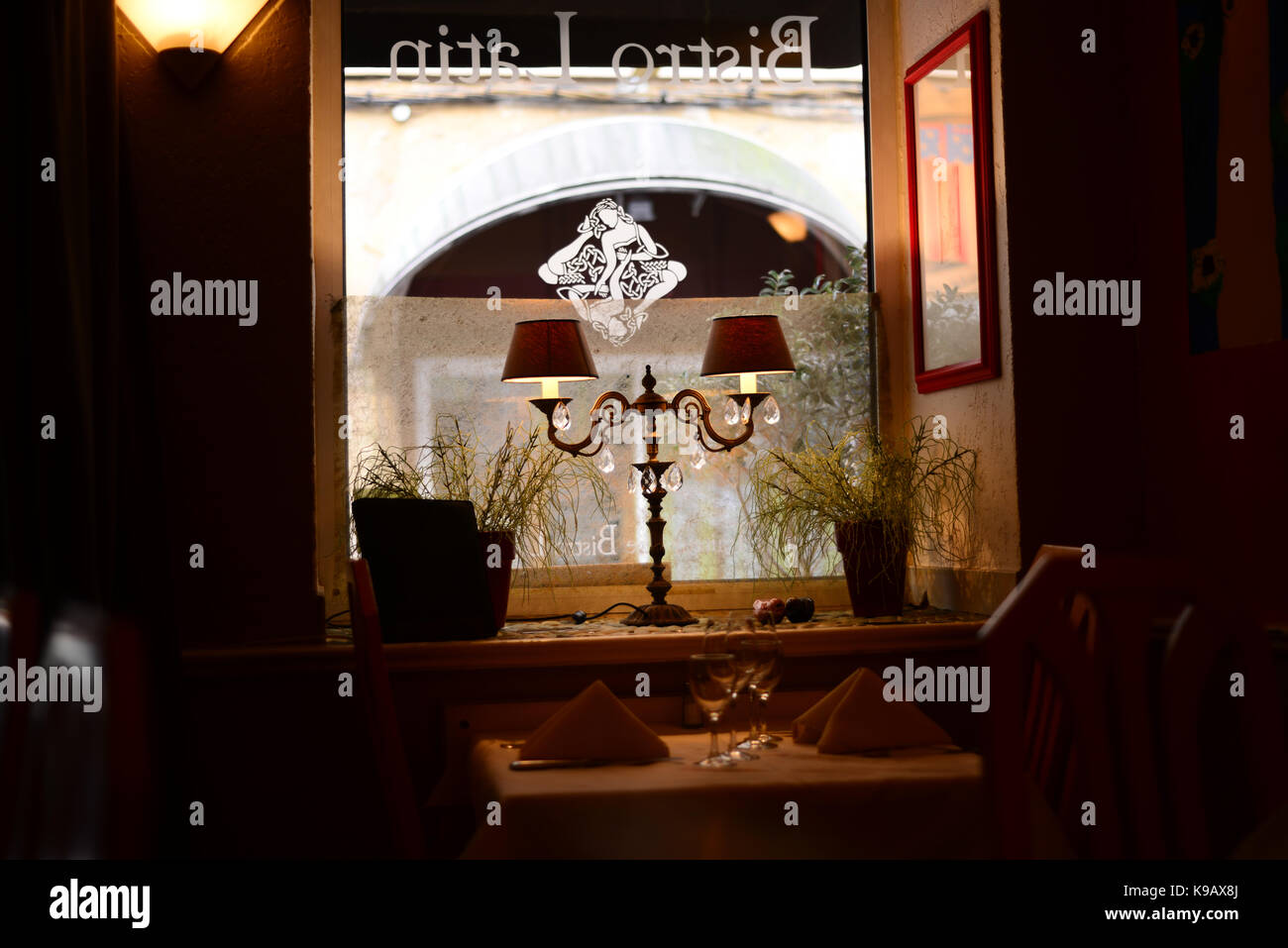 Cenate nel bistrot Provenza al tavolo vicino alla finestra con vista sulla strada e doppio supporto lampada Foto Stock