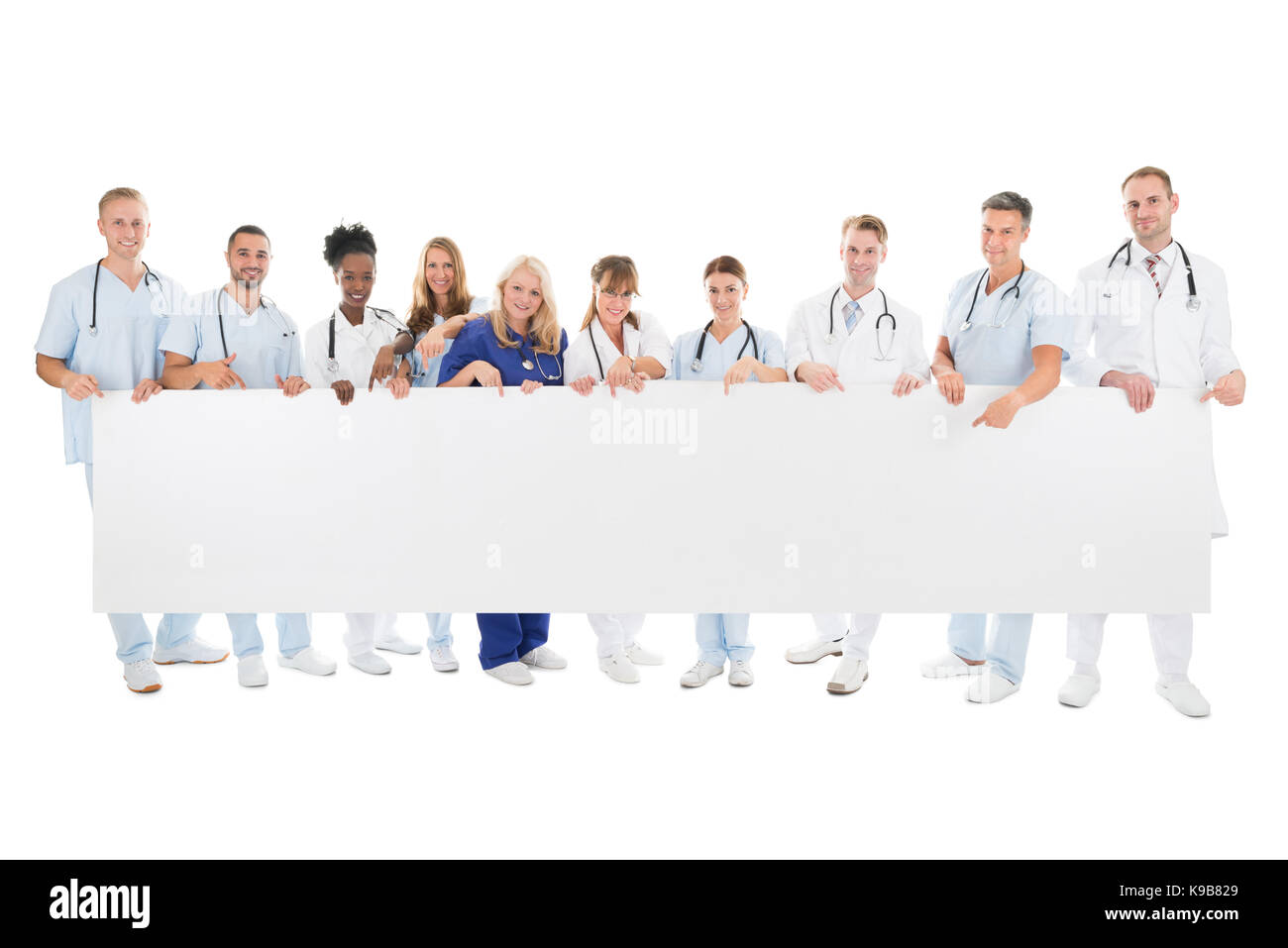 A piena lunghezza Ritratto di fiducioso multietnica team medico tenendo blank billboard contro uno sfondo bianco Foto Stock