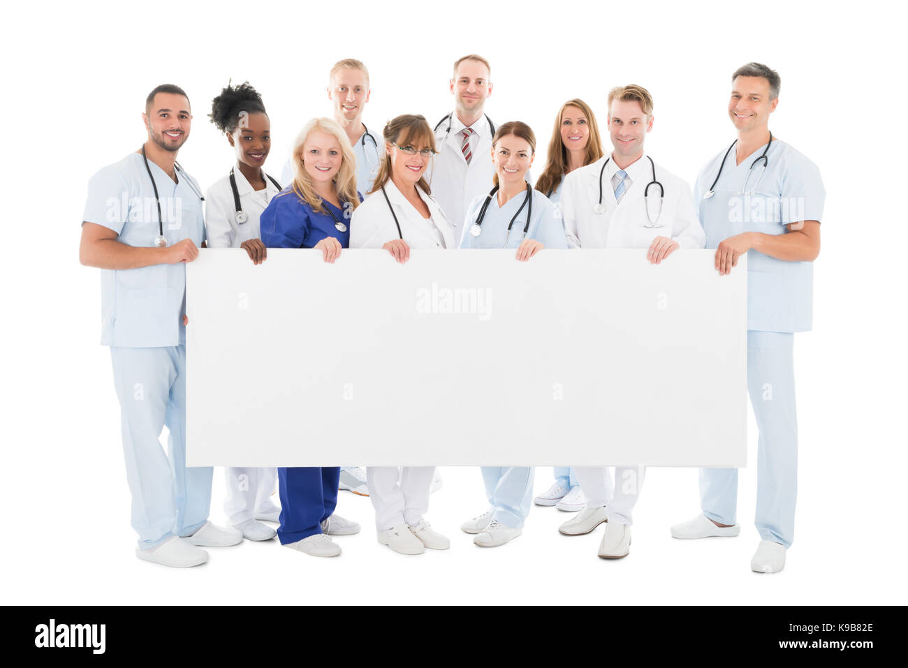 A piena lunghezza Ritratto di fiducioso multietnica team medico tenendo blank billboard contro uno sfondo bianco Foto Stock