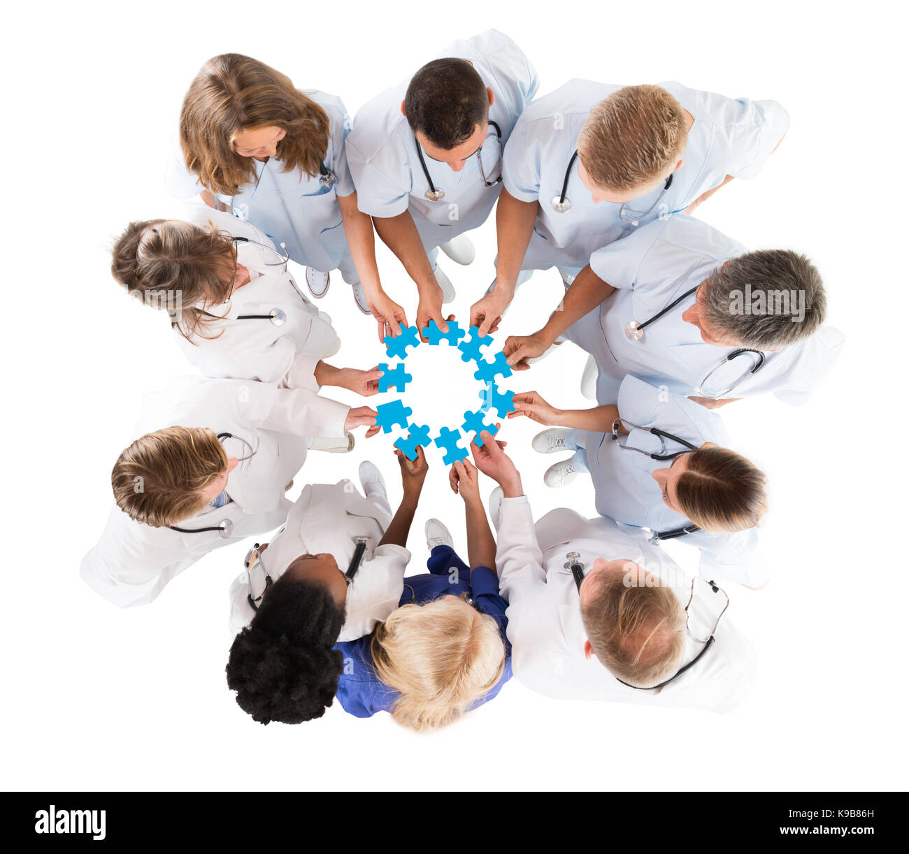 Direttamente sopra il colpo del team medico unire pezzi sagomati azzurri contro uno sfondo bianco Foto Stock