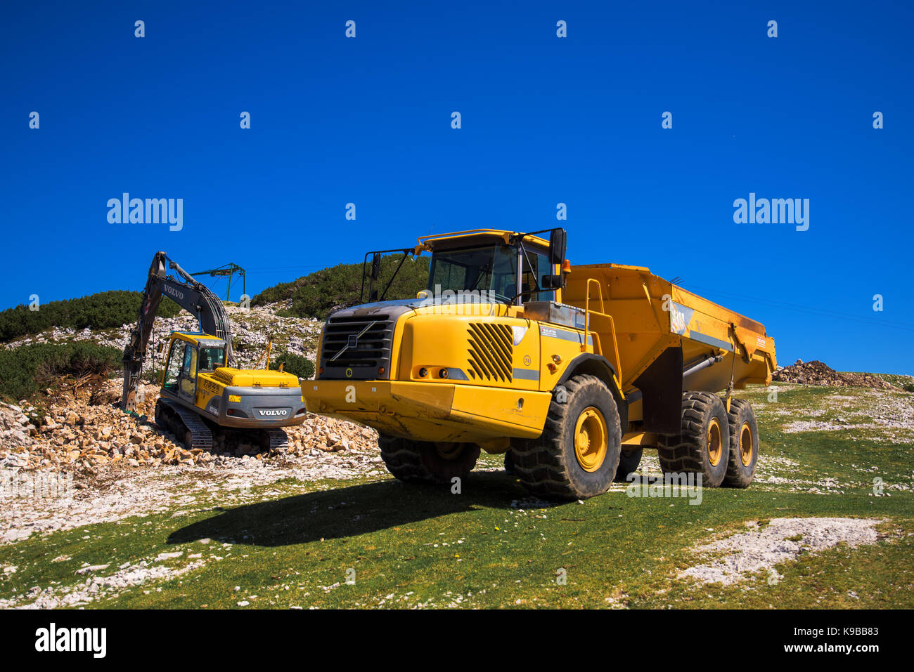 Vogel mountain, Slovenia - 30 agosto 2017: costruzione di macchinari per la frantumazione di pietra, volvo bulldozer e camion grande dumper lavorando su slop di montagna Foto Stock