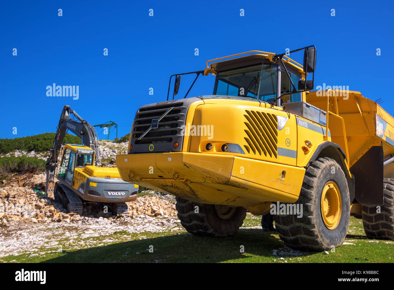 Vogel mountain, Slovenia - 30 agosto 2017: costruzione di macchinari per la frantumazione di pietra, volvo bulldozer e camion grande dumper lavorando su slop di montagna Foto Stock