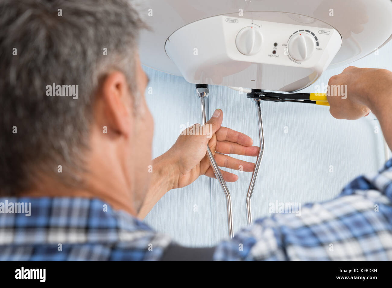 Close-up di metà maschio adulto plumber installazione del riscaldatore di acqua Foto Stock