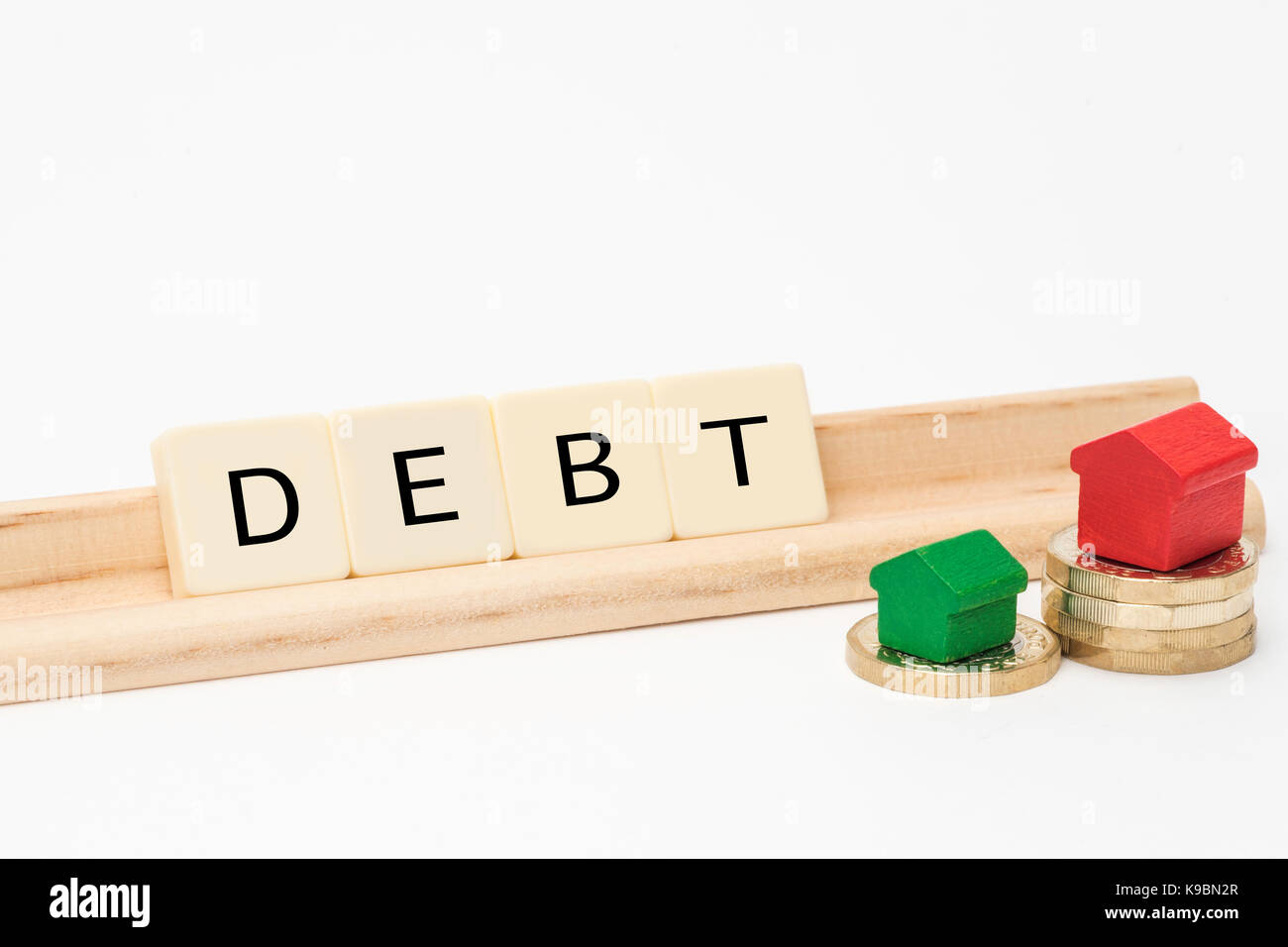 Finanze Parola correlati precisato con lettera di piastrelle. Isolato su sfondo bianco con il giocattolo di legno case sulla sommità del British una libbra di monete Foto Stock