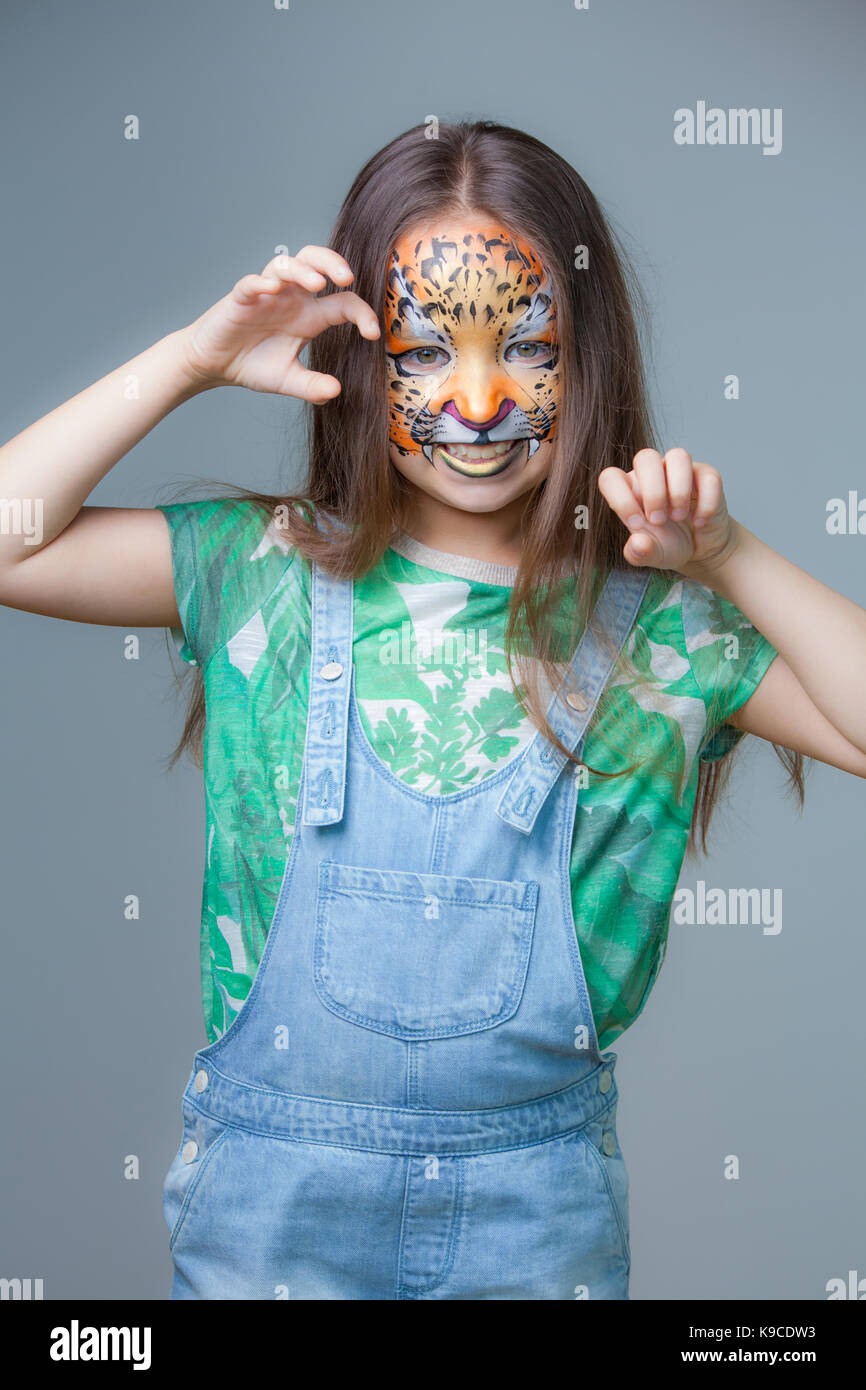 Bellissima ragazza con una tigre dipinta sul suo volto su sfondo grigio Foto Stock